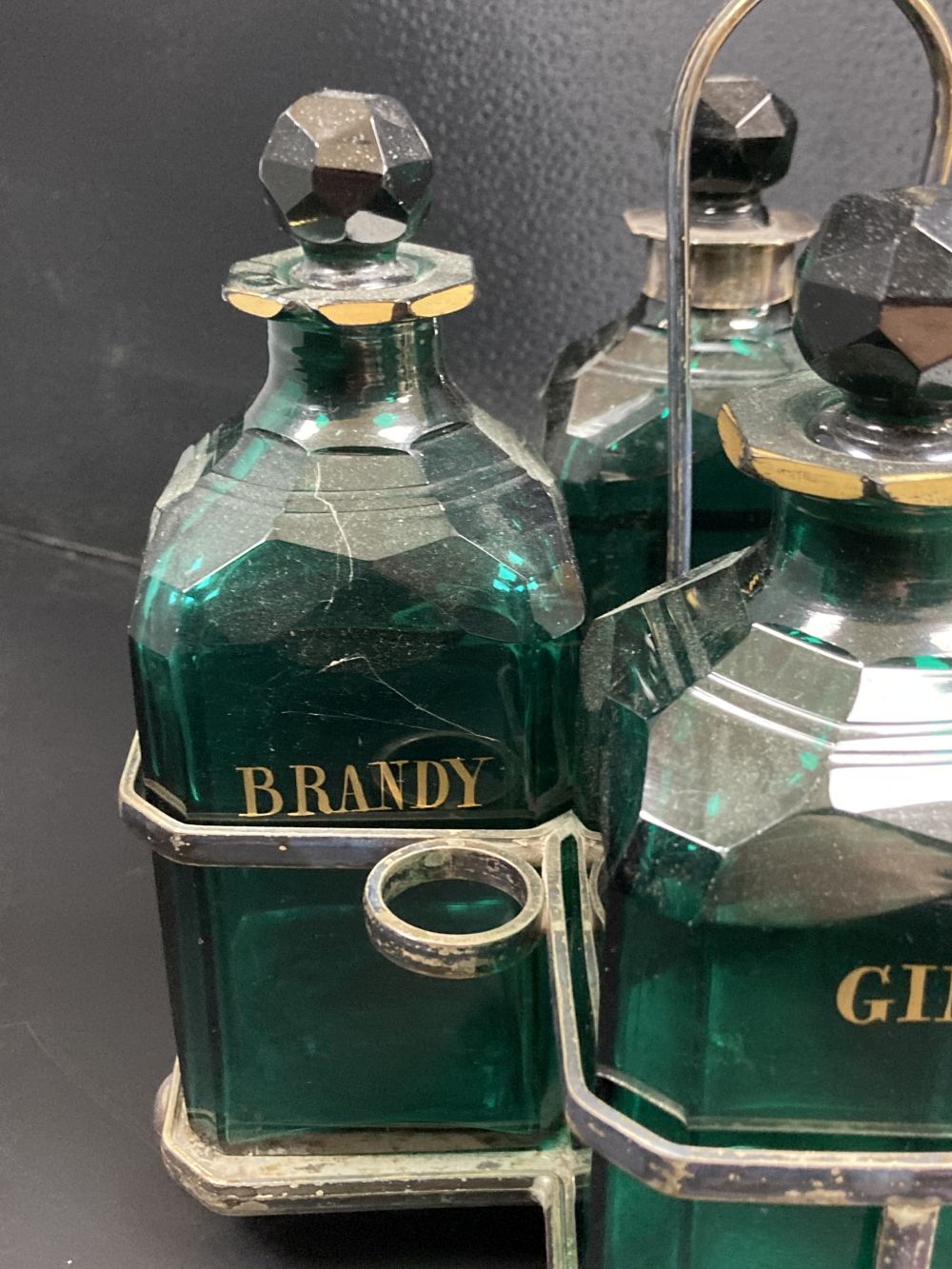A set of four Victorian cut green glass spirit bottles, in a plated frame, 28cm,